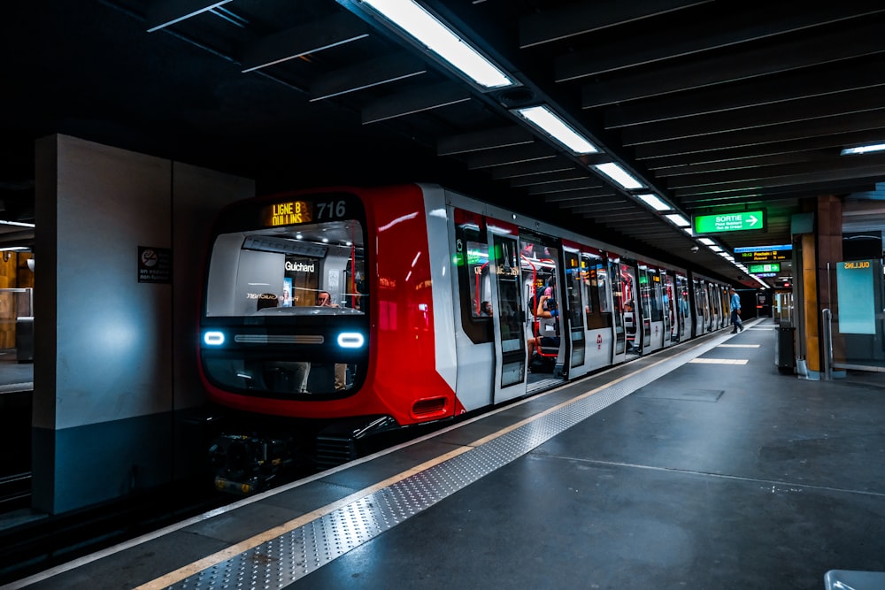 a red and white train pulling into a train station