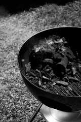 Charcoal grill with smoke rising, surrounded by fresh vegetables ready to be grilled.