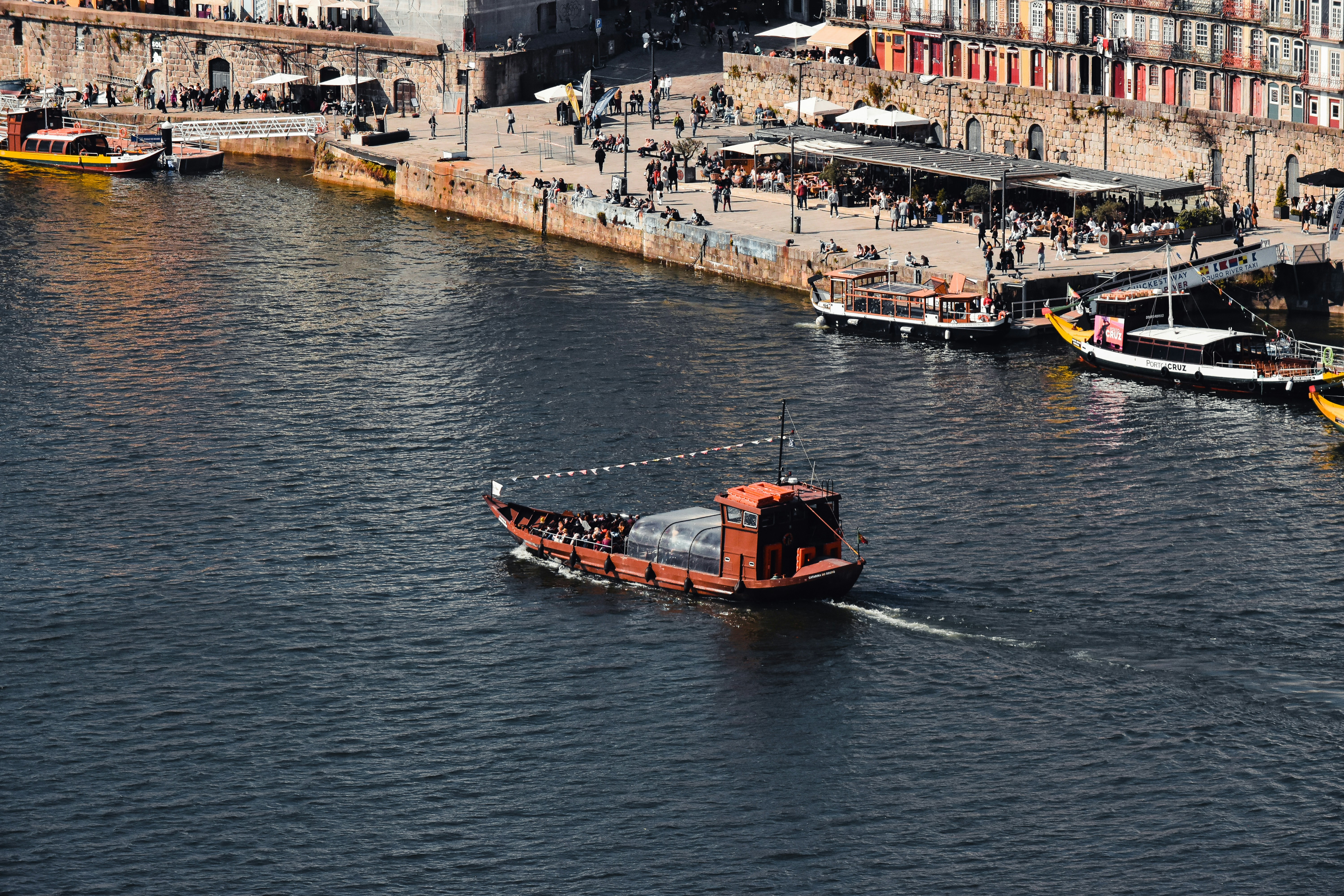 a small boat traveling down a river next to a city, 