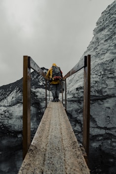 a man with a backpack walking across a bridge