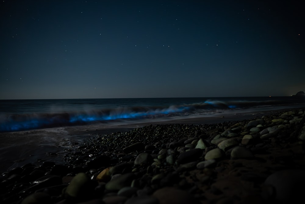 a night time view of a beach with blue smoke coming out of the water