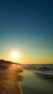 A golden sunset over a serene beach with a lone traveler walking along the shore, evoking the spirit of adventure.