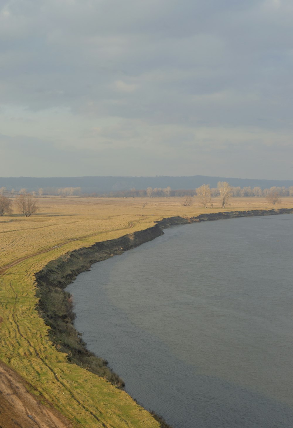 a large body of water sitting next to a lush green field