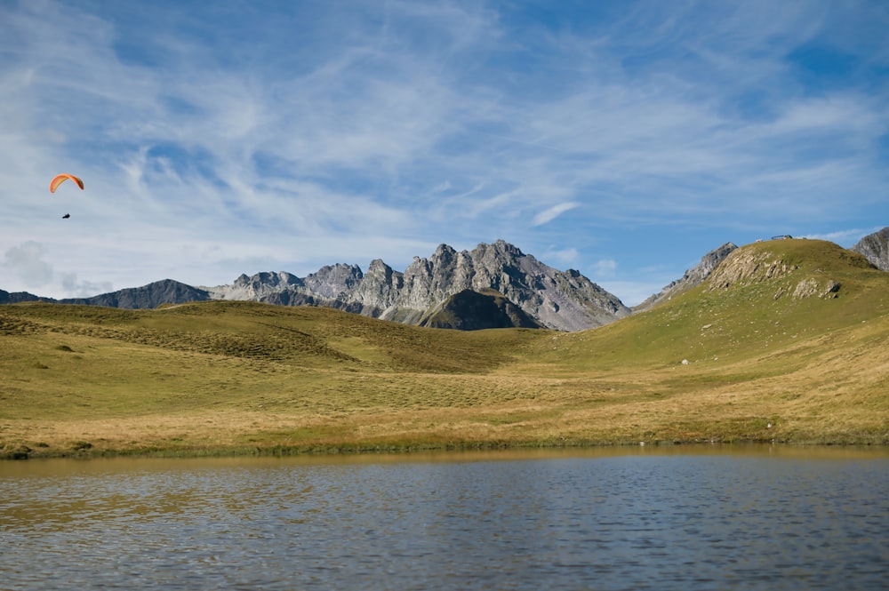 a paraglider flying over a lake in the mountains