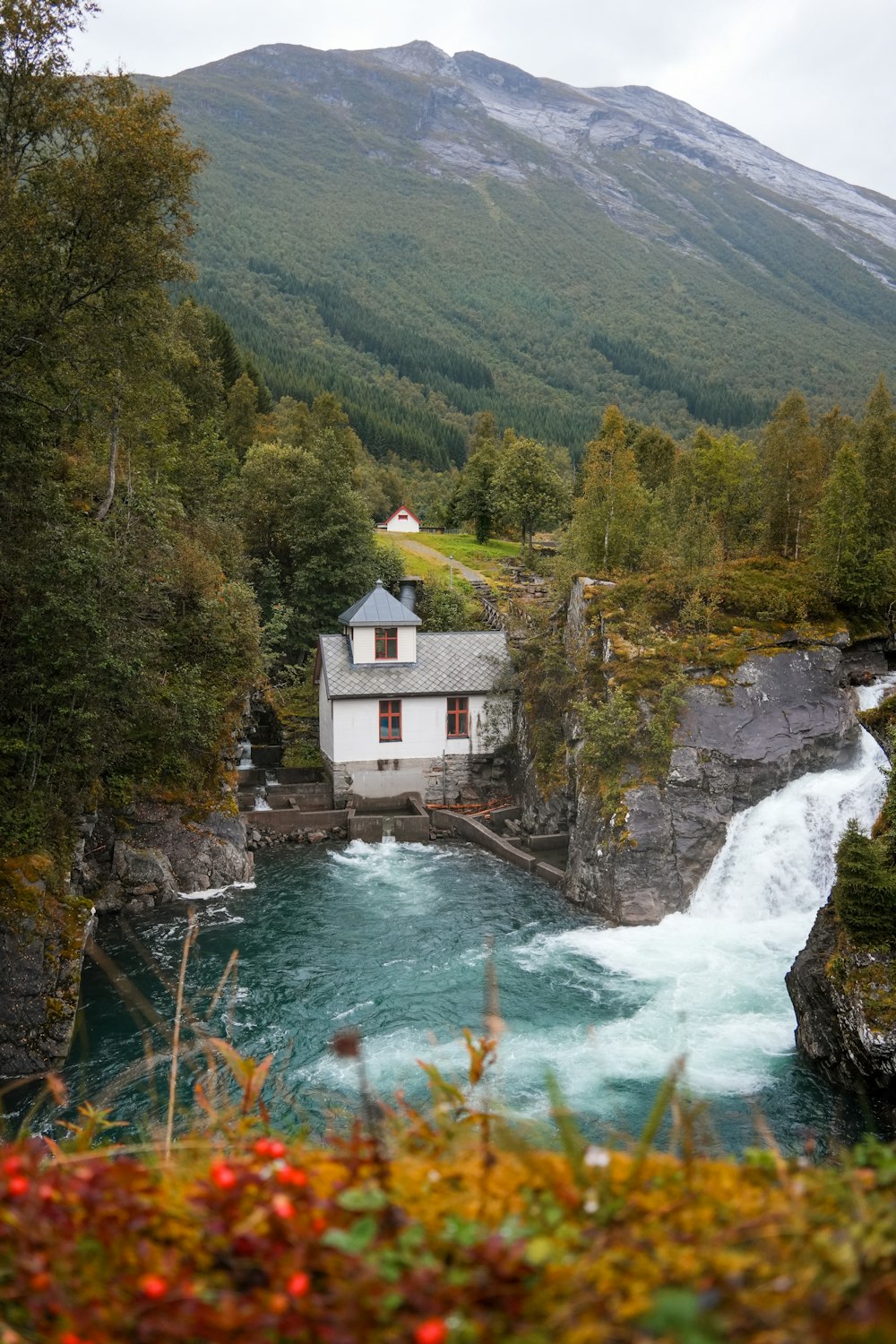 a house sitting on top of a cliff next to a river