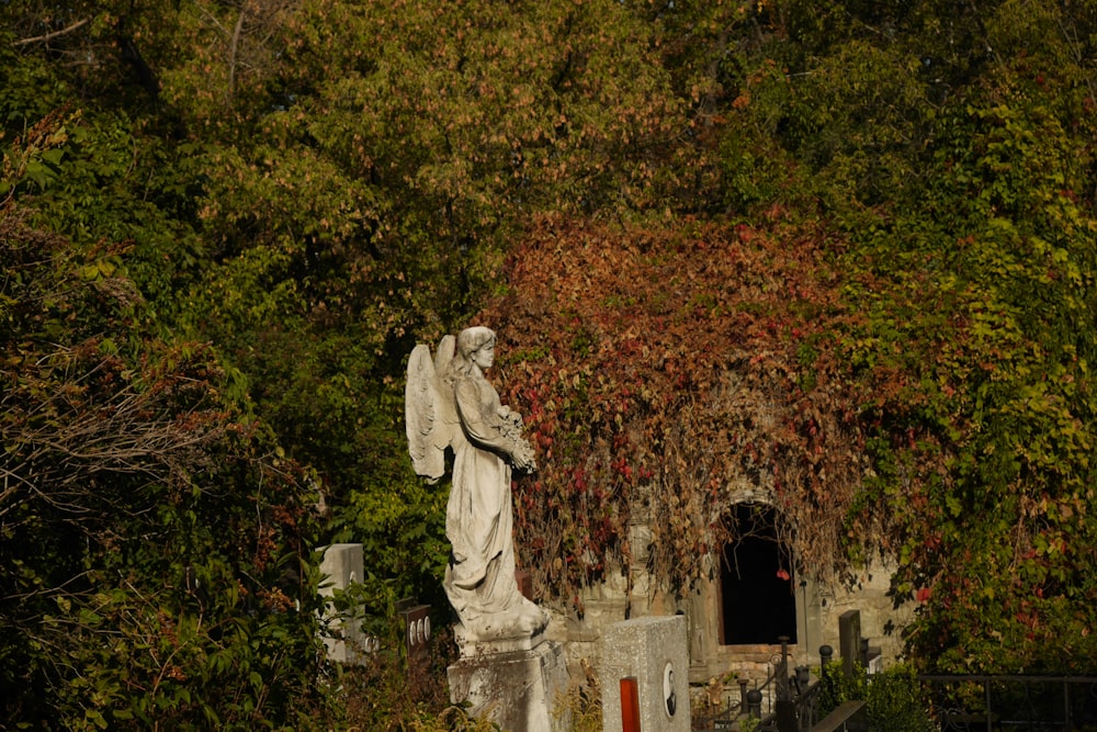 a statue of an angel in a cemetery surrounded by trees