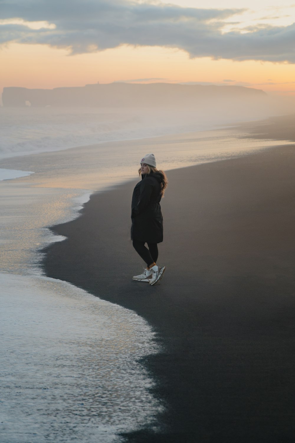 a woman standing on a beach next to the ocean