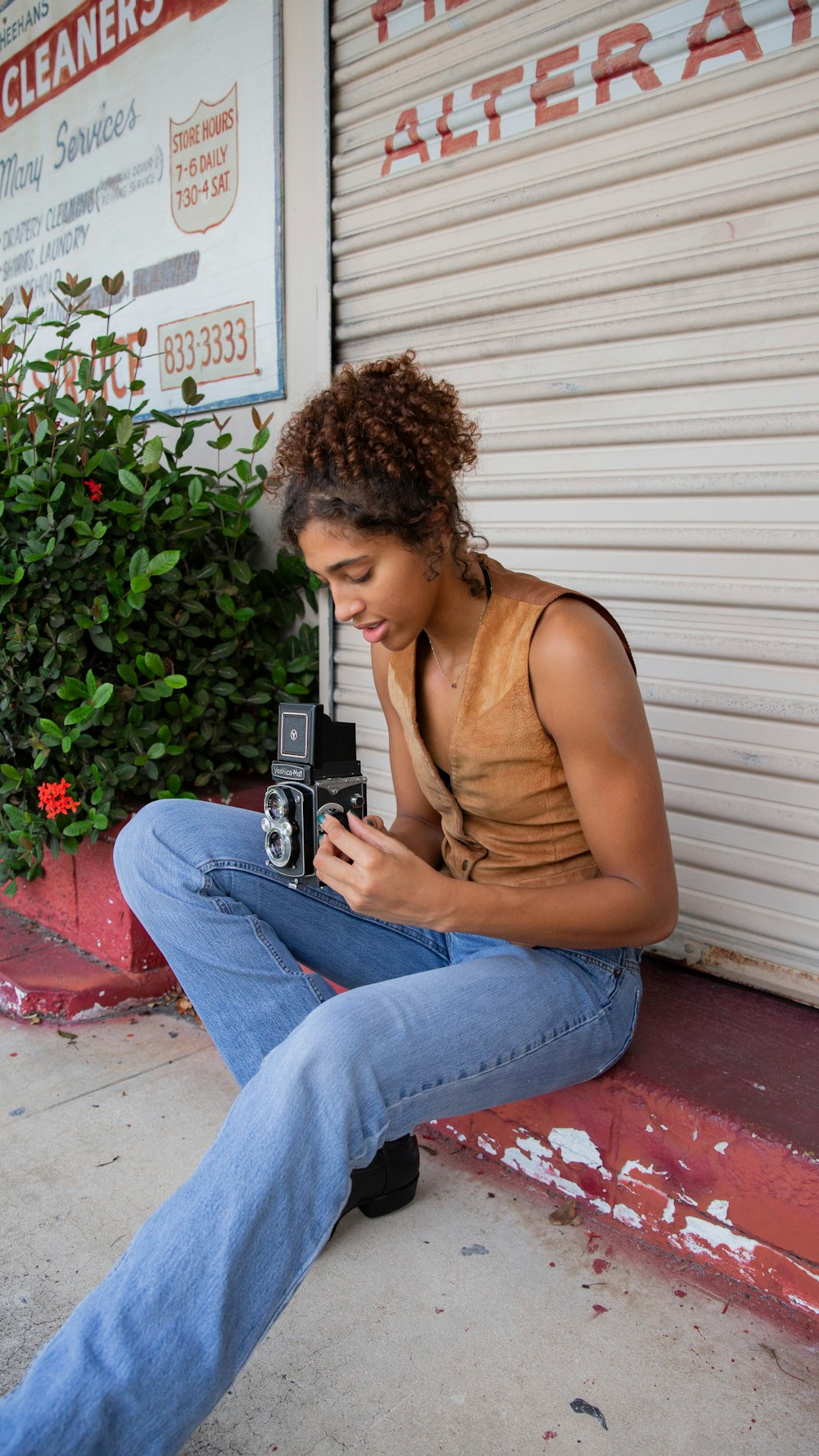a woman sitting on a curb with a camera