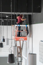 a man standing on a ladder working on a light fixture