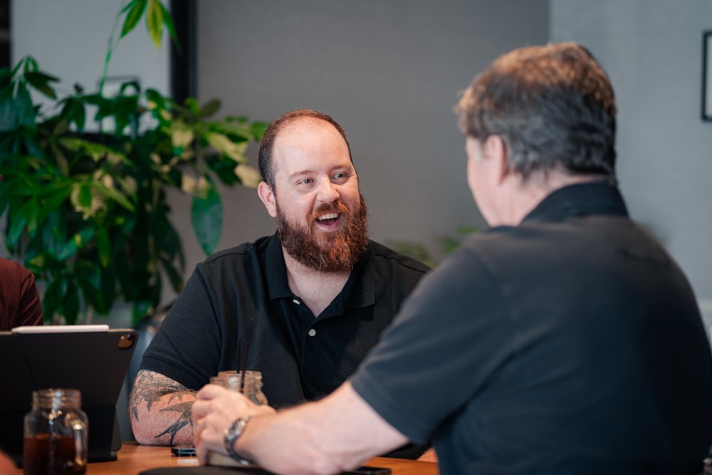 two men sitting at a table talking to each other