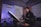 A person sits at a desk in a modern studio, working on a computer. The room features soundproof panels on the walls and ambient lighting.
