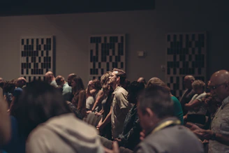 A diverse group of passionate leaders gathered in a warm, sunlit room engaged in deep discussion and prayer.