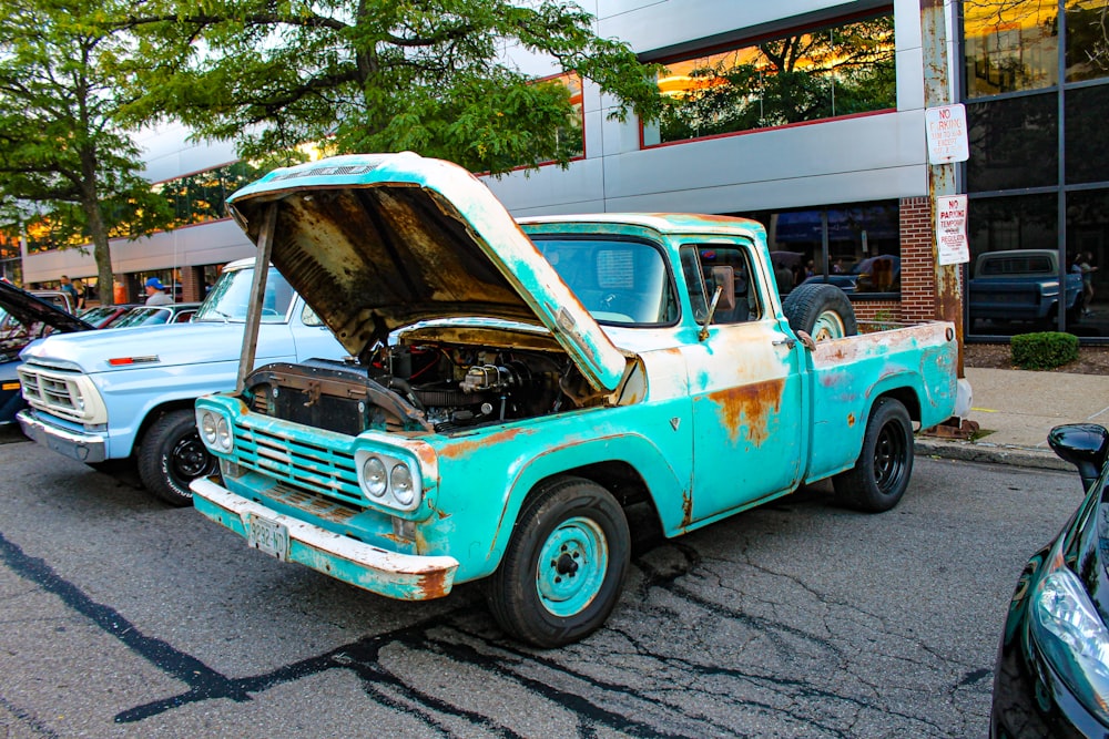 an old truck with a hood open parked on the side of the road