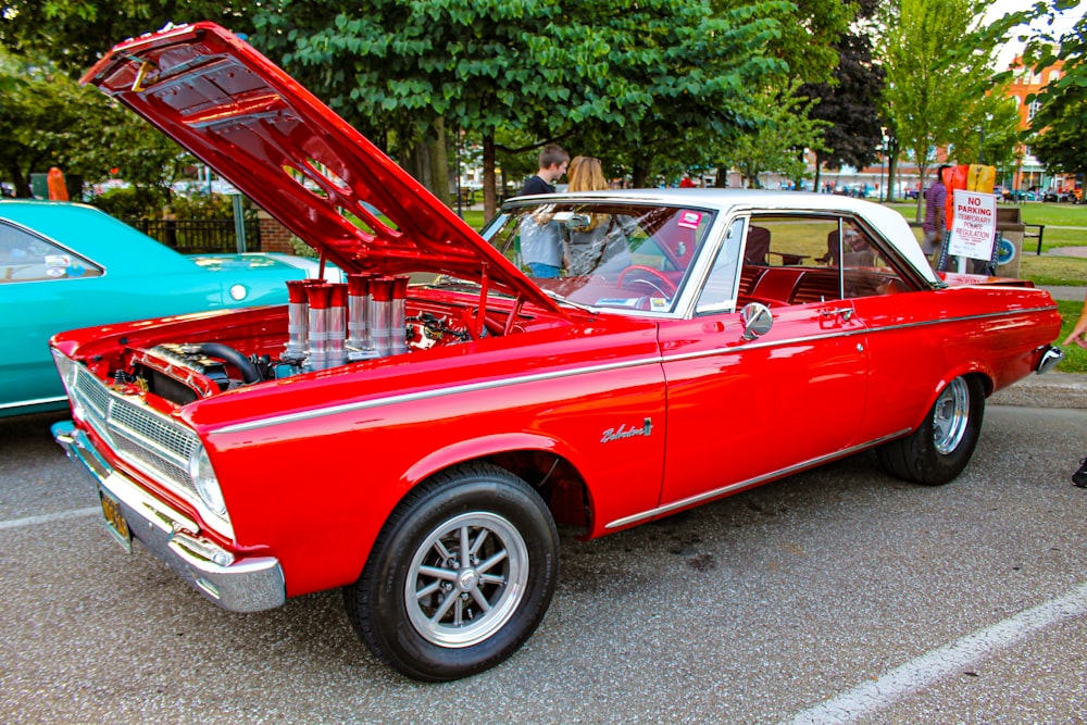 a red car with its hood open in a parking lot