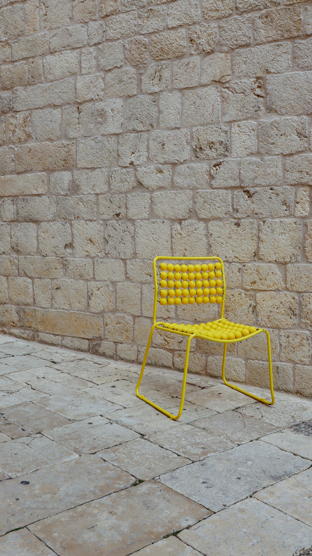 a yellow chair sitting in front of a brick wall