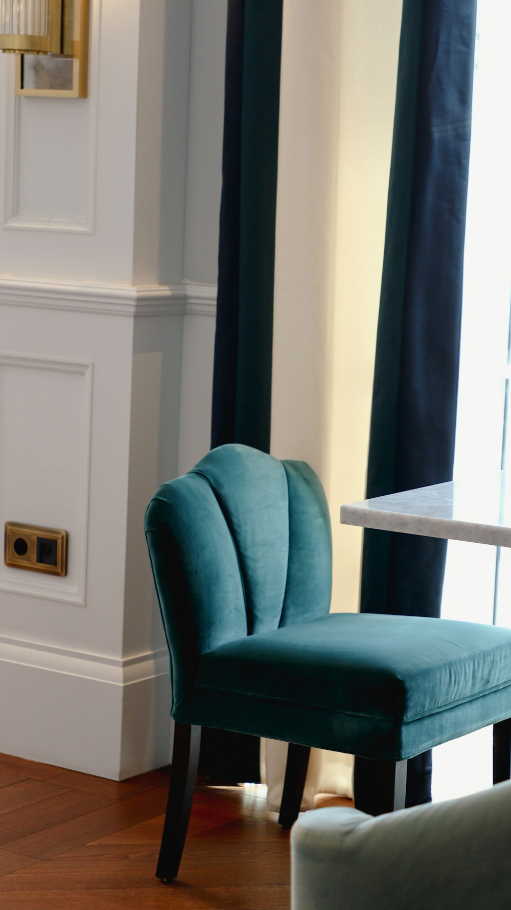 a blue chair sitting in a living room next to a window