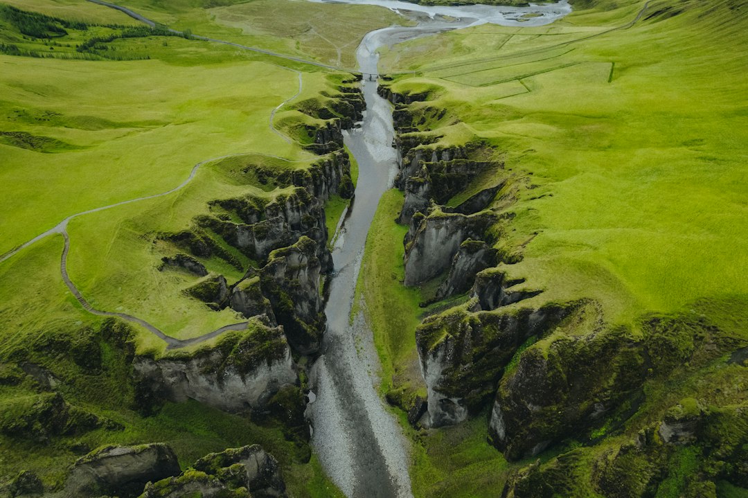 a river running through a lush green valley, Fjadrargljufur