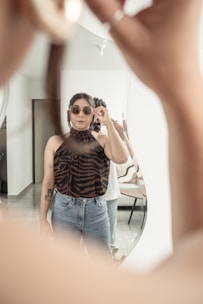A person trying on a pair of fashionable sunglasses in front of a mirror.