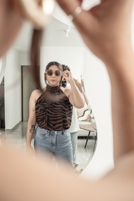 A person trying on a pair of fashionable sunglasses in front of a mirror.