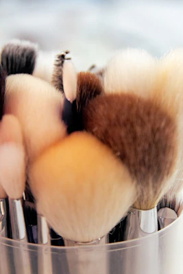 Various makeup brushes with soft bristles resting beside a foundation bottle and blush compact.