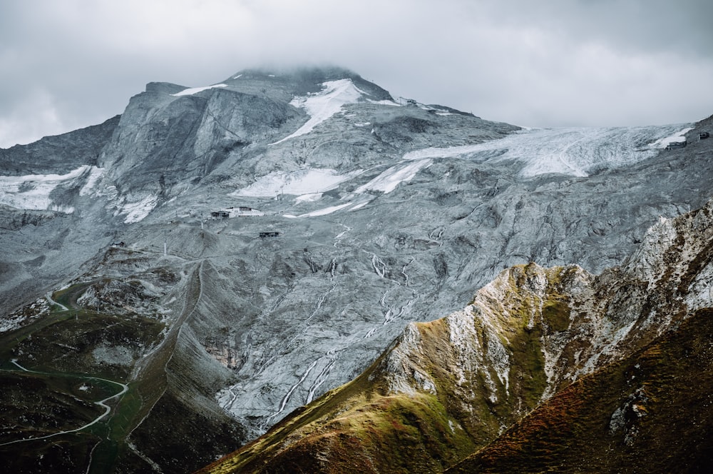 a snow covered mountain with a winding road in the foreground