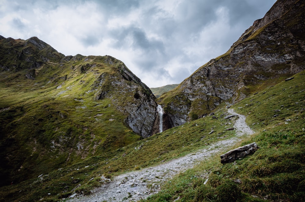 a path leading to a waterfall in the mountains