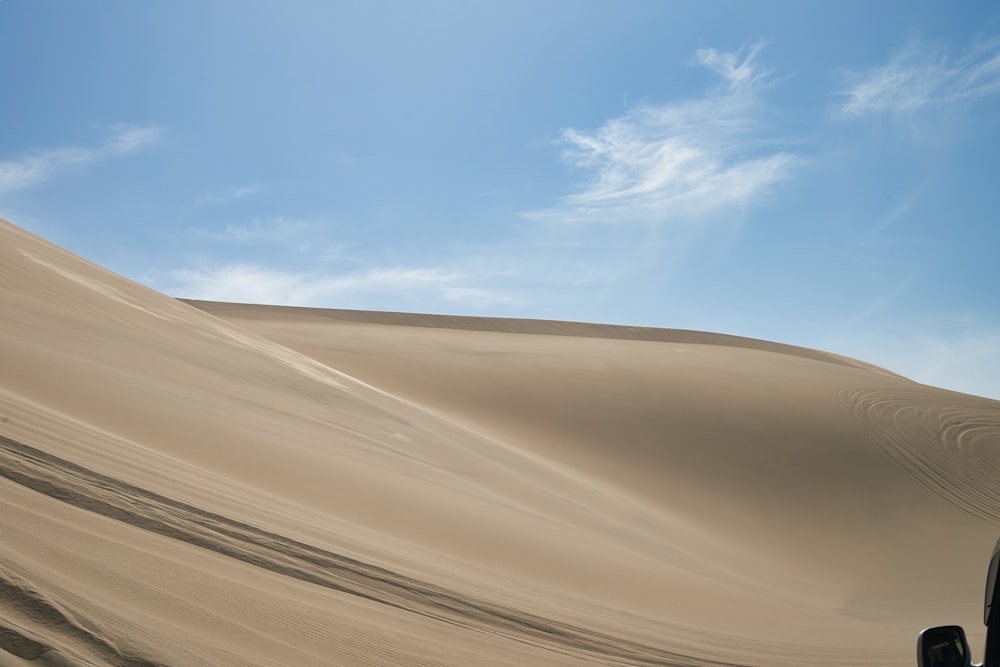 a car driving down a sandy hill under a blue sky