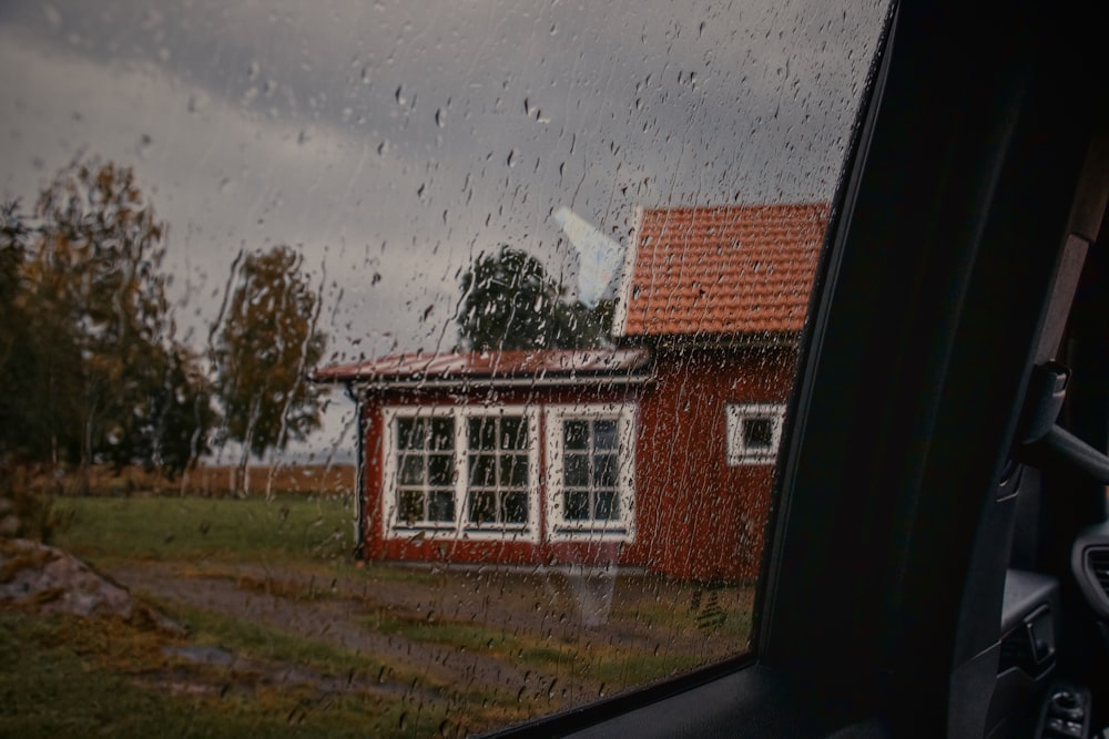a red house is seen through a rainy window