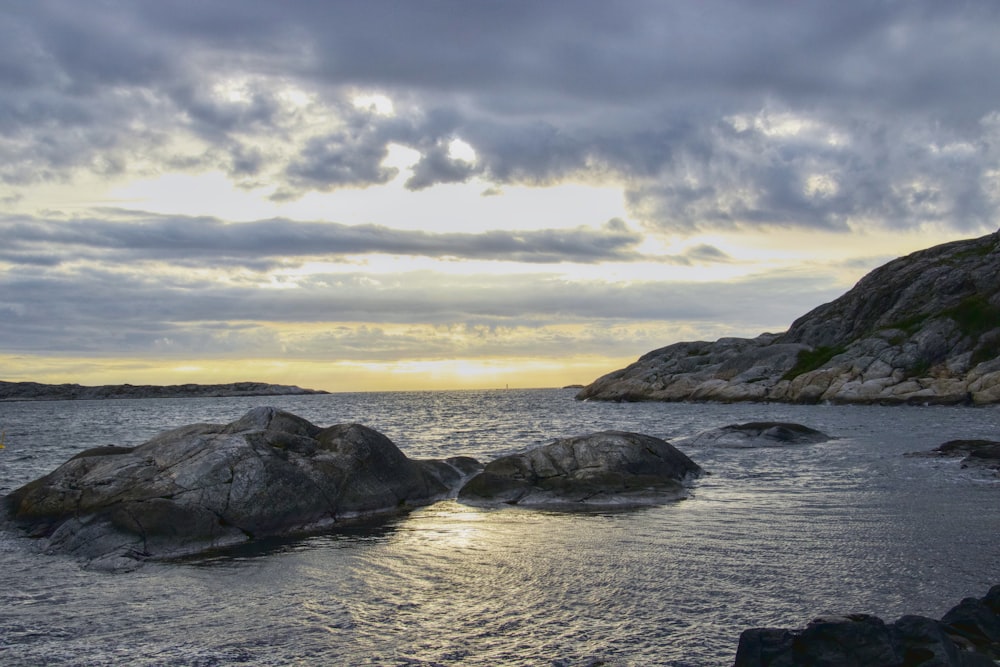 a body of water surrounded by rocks under a cloudy sky