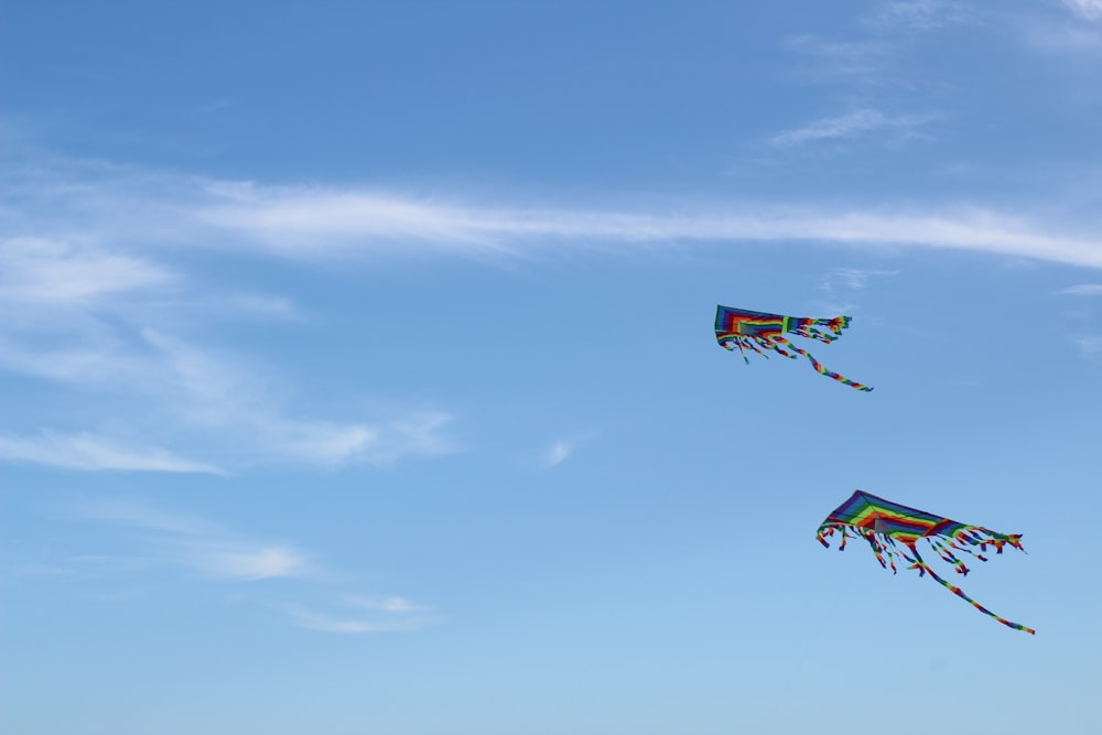 two kites flying in the sky on a sunny day