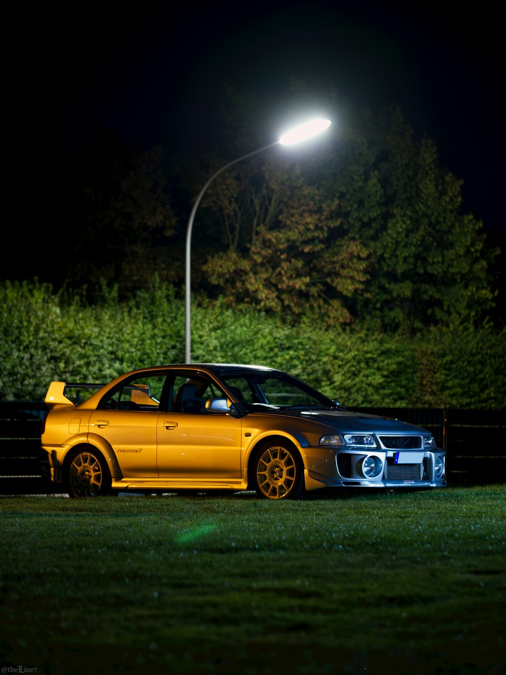 a yellow car parked next to a black car at night