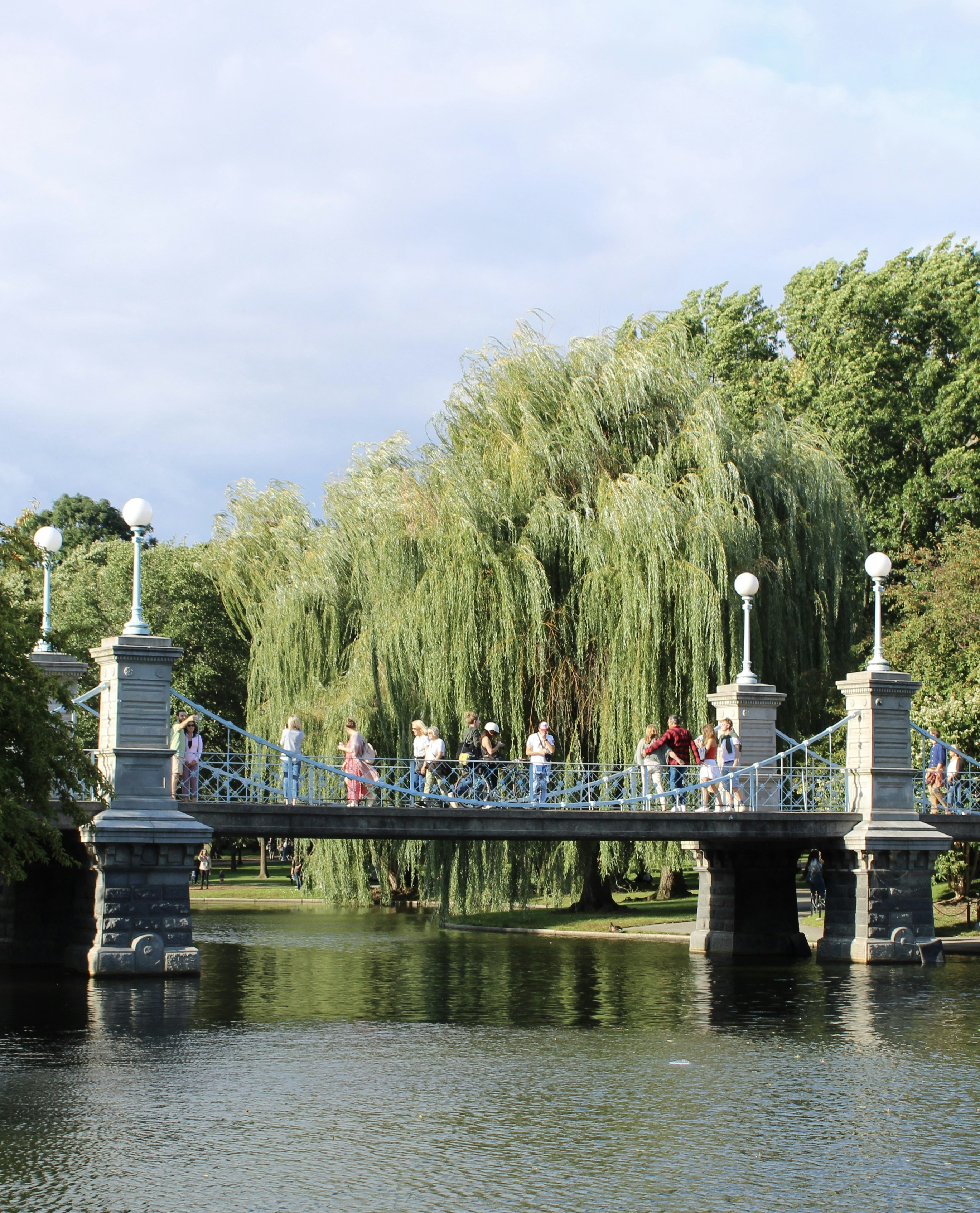 a group of people walking across a bridge over a river