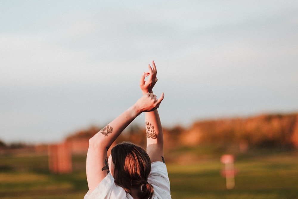 a woman in a white shirt reaching up to catch a frisbee