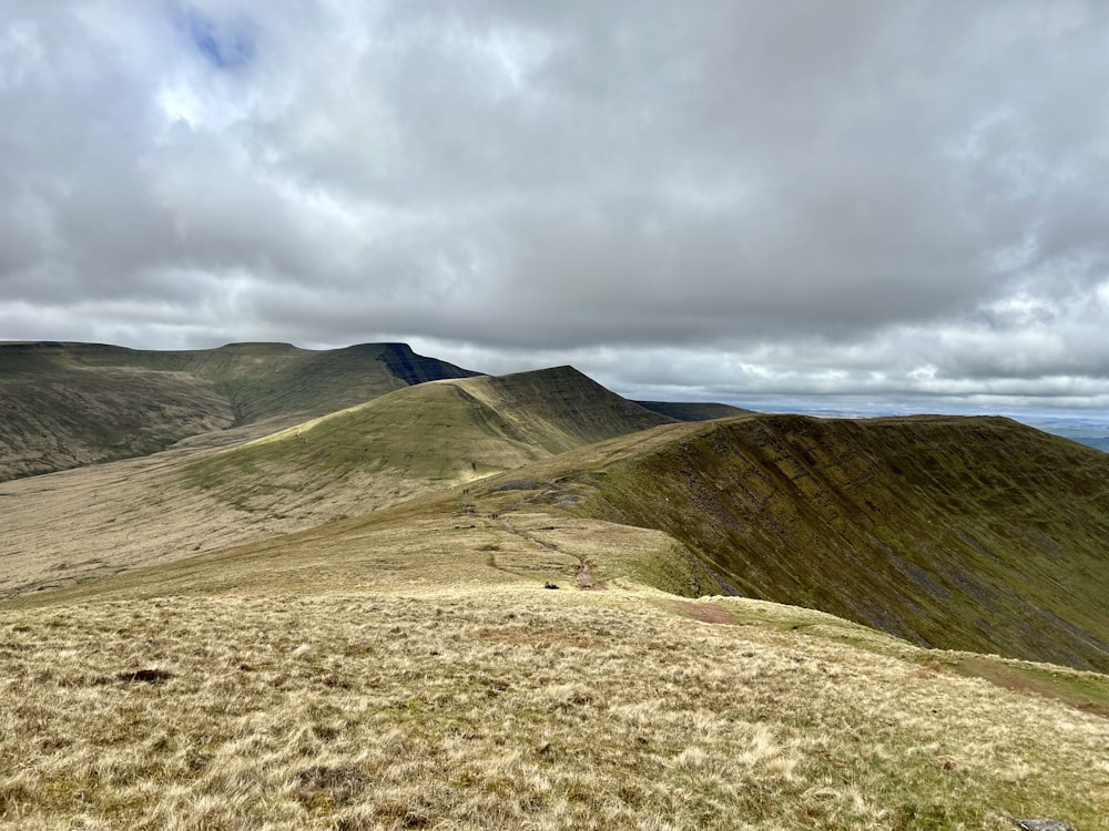 a grassy hill with a few hills in the background