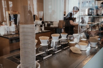 a coffee shop counter with coffee cups stacked on top of each other
