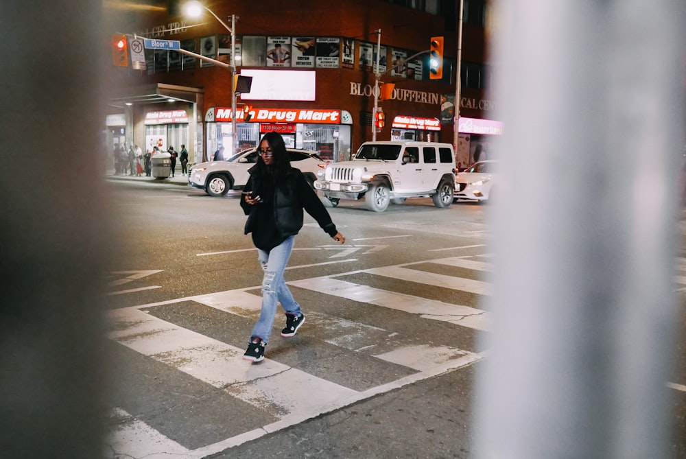 a woman walking across a street at night