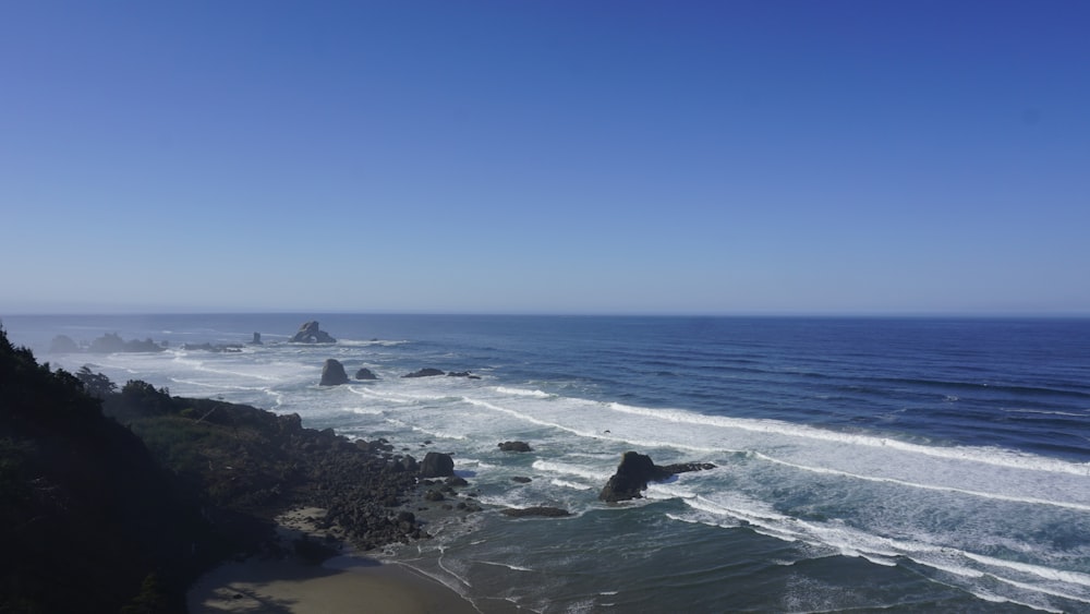 a person swimming in the ocean next to a cliff