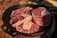 Several raw beef shank cuts with bone are placed inside a black cast iron skillet. The meat appears fresh with visible marbling, highlighting a rich red color. The skillet rests on a wooden surface, suggesting a rustic kitchen setting.