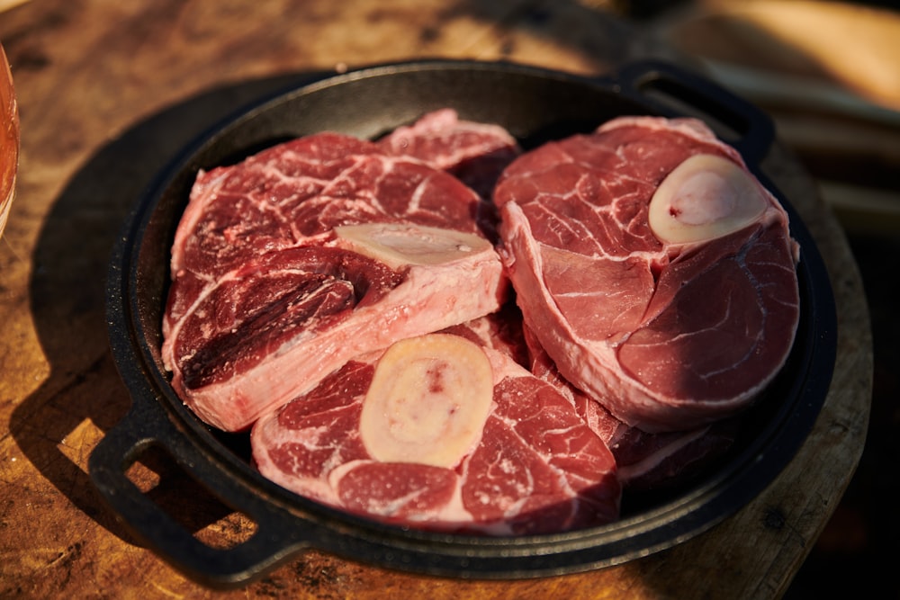raw meat in a frying pan on a wooden table