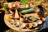 A rustic wooden table displaying ingredients for a homemade vegetable soup with fresh herbs.