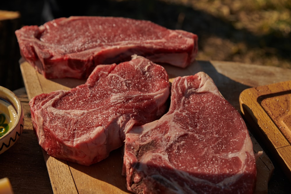 ein paar Steaks, die auf einem hölzernen Schneidebrett sitzen