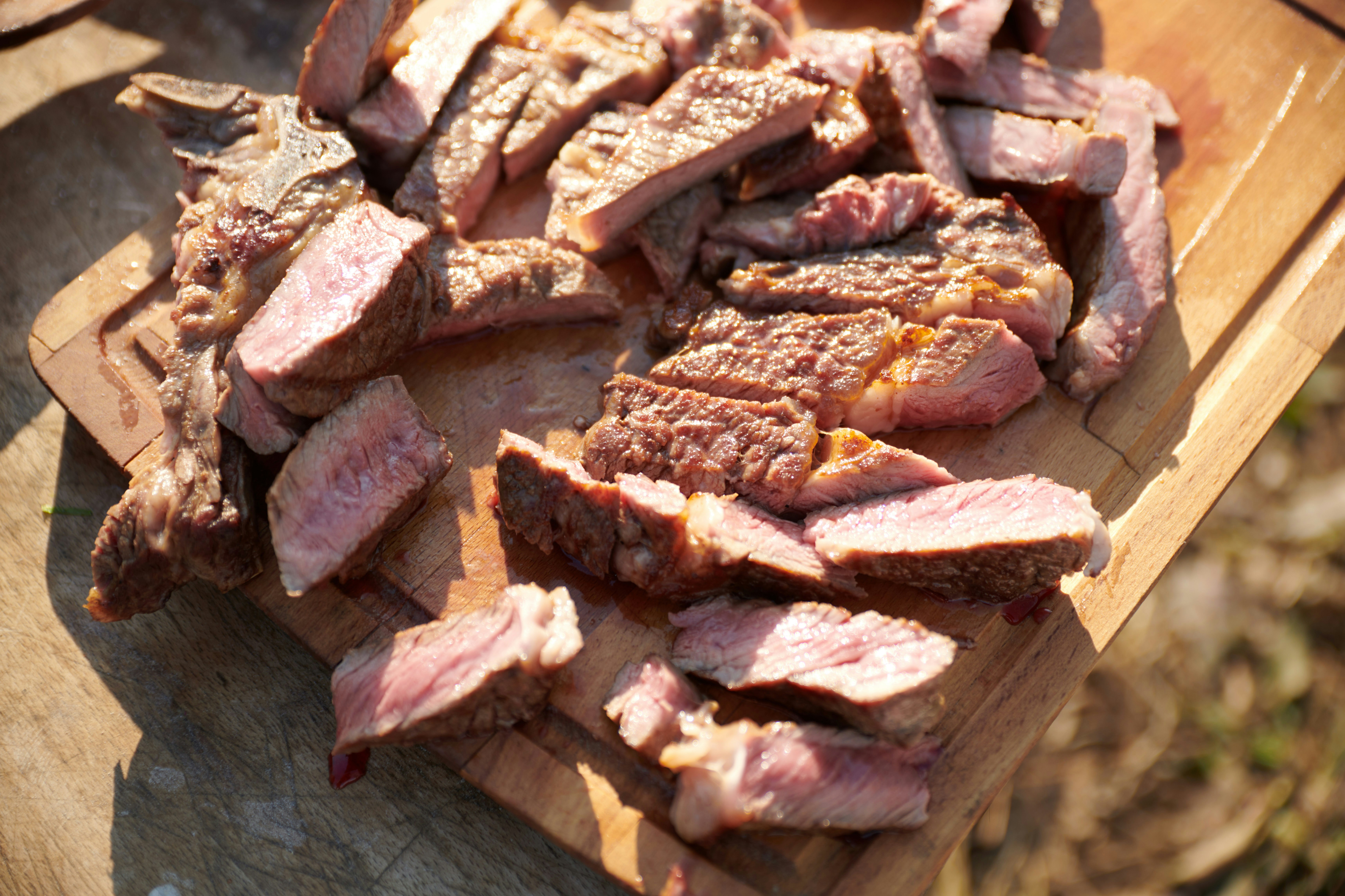 Homemade high-protein steak treats prepared for dogs, sliced on a wooden cutting board.