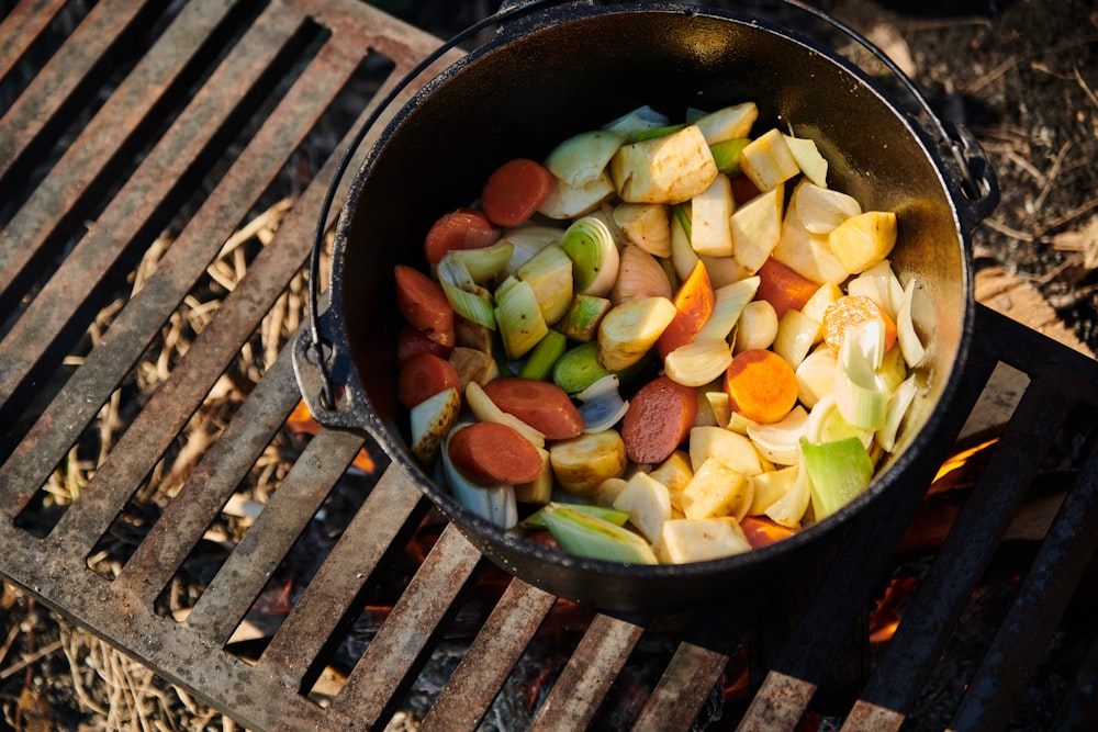 a pot filled with vegetables sitting on top of a grill