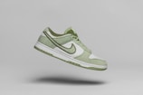 a pair of green and white shoes flying through the air