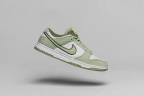 a pair of green and white shoes flying through the air