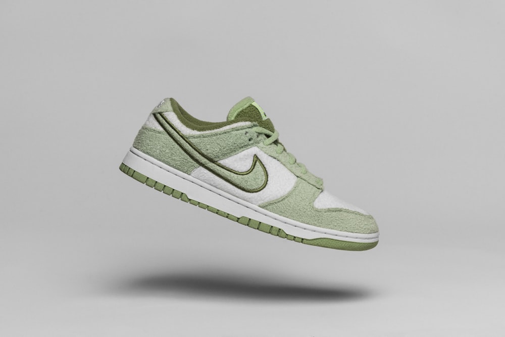 ein Paar grün-weiße Schuhe, die durch die Luft fliegen