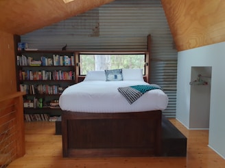 Cozy bedroom scene featuring a wooden platform bed with linen nightstands and rustic wall signs.
