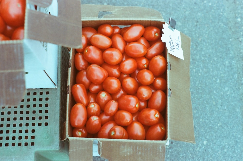 a cardboard box filled with lots of red tomatoes