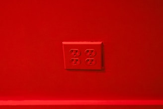 A red wall with a set of four electrical outlets in the center.