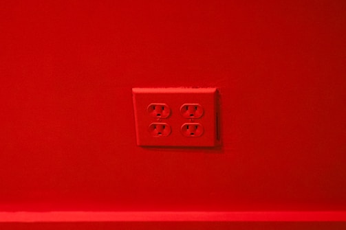 A red wall with a set of four electrical outlets in the center.